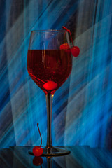 Glass of aperol spritz cocktail with cherry on a dark background. Light painting.