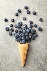 Waffle cone with ripe blueberries on light table