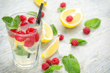 Glass of fresh raspberry mojito on wooden table