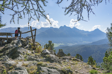 senior woman, taking a break from her Mountainbike trip and looking over the valley of upper Engadin above Celerina and Saint Moritz, Graubuenden, Switzerland