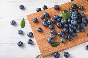 Board with ripe blueberries on wooden table