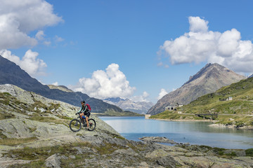 Fototapeta na wymiar senior woman, riding her e-mountainbike on the famous Bernina express trail at Lago Bianco, Bernina Pass near Pontresina an St.Moritz, Engadin, Switzerland