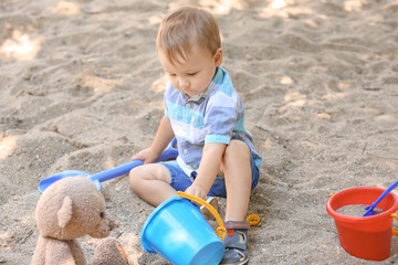 Cute little boy playing in sandbox outdoors