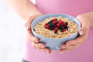 Woman with bowl of tasty oatmeal, closeup