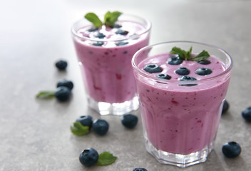 Glasses of tasty blueberry smoothie on light table