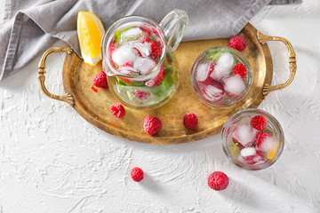Glasses and jug of fresh raspberry mojito on white table