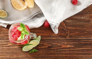 Mason jar of fresh raspberry mojito on wooden table