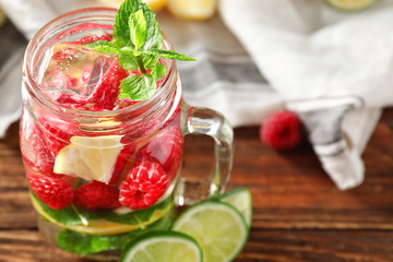 Mason jar of fresh raspberry mojito on wooden table, closeup