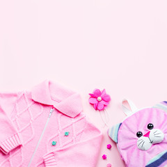 Little girl clothes collection flat lay with cardigan, backpack on pink background.
