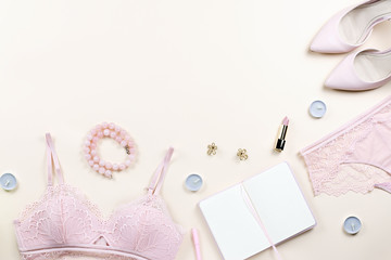 Fashion blogger workspace with woman elegant pink lace bra and panties, pumps and note book. Stylish lingerie flat lay.