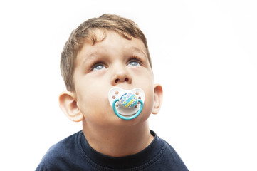 A little boy with a dummy in his mouth looks up. Isolated
