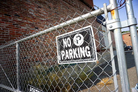 no parking sign on chain link fence - Powered by Adobe
