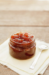 Homemade apple jam in small jar on a napkin on a wooden table. Rustic style.