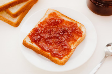 Toast with a crumpled apple jam on a plate on white table. Delicious sweet breakfast.