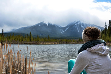 Woman Looking Across a Lake at Mountains