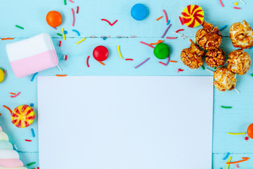 Frame for the text on the background of different, sugar, children's sweets. Candies on a blue, wooden background. Copy space, sweets concept