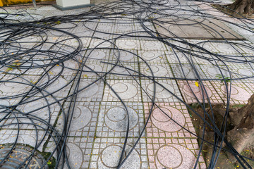 Power cord and Cable power tangled on the Walkway, floor and circle drain hose and Tree root.