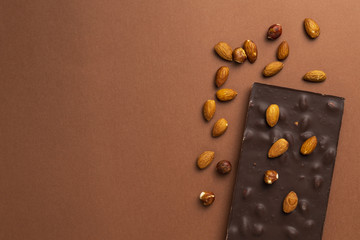 Dark chocolate bar with roasted almonds scattered around