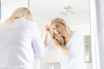 Woman looking hair in a mirror