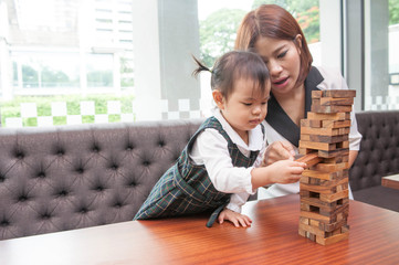 Fototapeta na wymiar Asian mom teaching her daughter for play wooden block game,selective focus