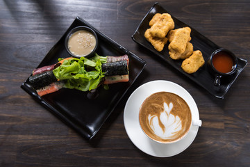 Latte art coffee cup with roll salad and chicken nugget on wooden table, top view