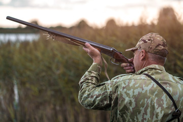 Hunting in the lake on wild ducks. Hunter in uniform with a hunting rifle