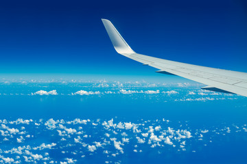 Looking through aircraft window during flight. Aircraft wing over blue skies and white clouds.Copy space.