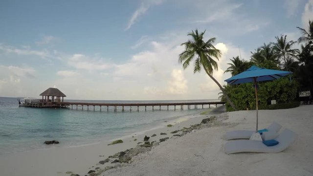 Time lapse of the beach with sand, umbrella, port, boat and tree at Maldives.