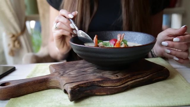 Girl appetizing eating soup Tom Yam.