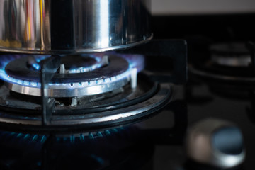 Boil water with stainless kettle on gas stove, blue flames on gas stove.