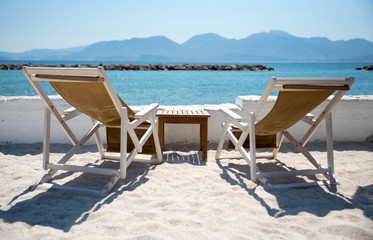Fototapeta na wymiar Two Deckchairs In Tropical Beach at quiet sea.