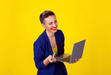 business woman laughing holding credit card and laptop