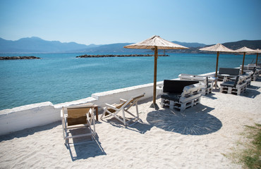 Two Deckchairs Under Parasol In Tropical Beach at quiet sea