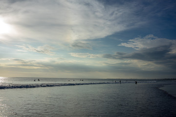 Fototapeta na wymiar people on beach in water at sunset