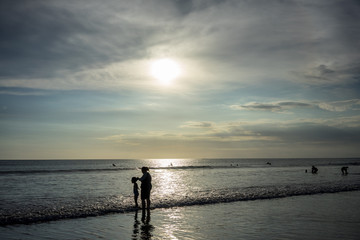 people on beach in water at sunset