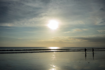 Fototapeta na wymiar people on beach in water at sunset