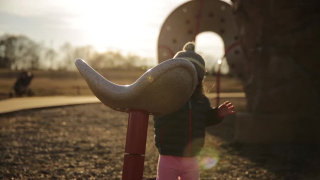 Little Girl on Playground in Winter Clothes Beautiful Fall Light