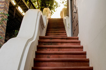 A staircase at a monastery, with a brownish floor and sunlight.