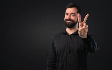 Handsome man with beard counting two on black background