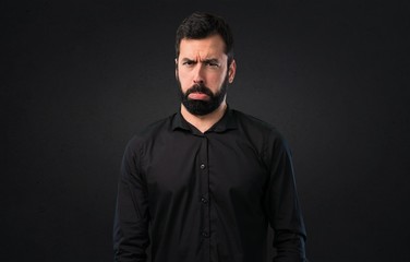 Fototapeta premium Sad handsome man with beard on black background