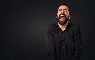 Handsome man with beard shouting on black background