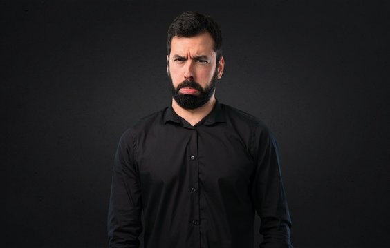 Sad handsome man with beard on black background