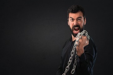 Handsome man with beard with chains on black background