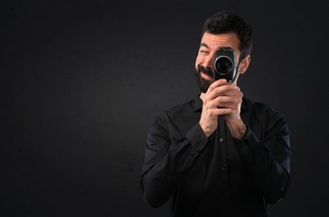 Handsome man with beard filming on black background