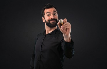 Handsome man with beard holding a big pencil on black background