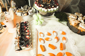 Delicious and tasty dessert table with cupcakes shots at reception closeup