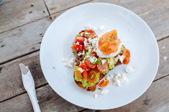 Healthy Breakfast with Wholemeal Bread Toast and Poached Egg with tomatoes, avokado, cheese and salmon on the wooden background.top view.Isolated