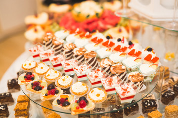 Delicious sweets on wedding candy buffet with desserts, cupcakes