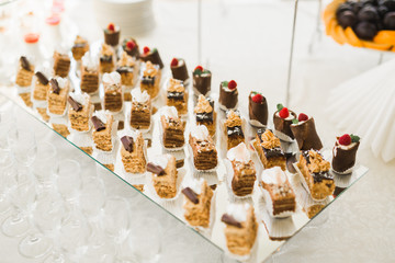 Delicious and tasty dessert table with cupcakes shots at reception closeup