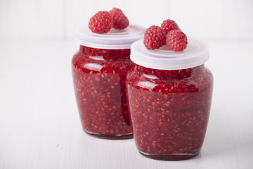 Raspberry jam in glass jars on a white table